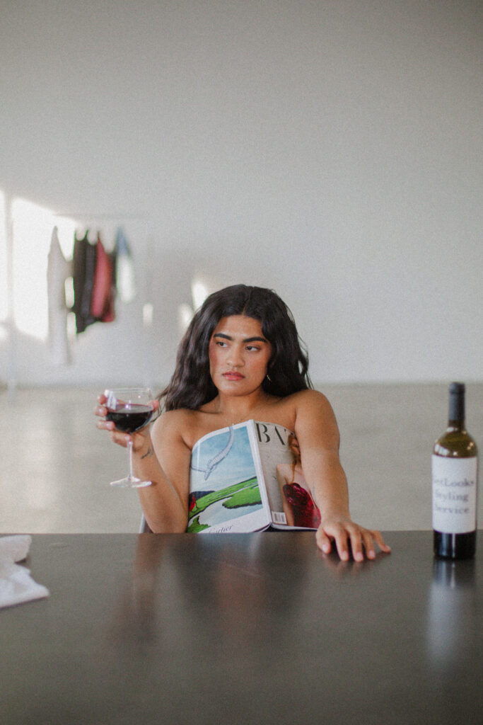 Topless model drinking wine behind a magazine